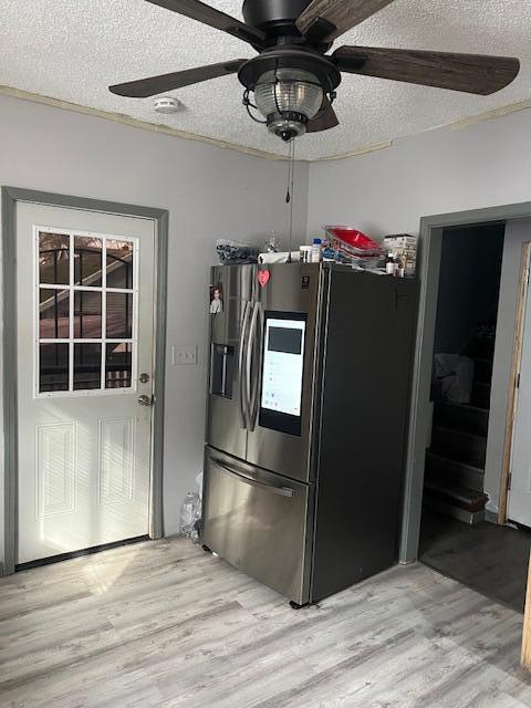 kitchen featuring a textured ceiling, light wood-style floors, a ceiling fan, and stainless steel fridge with ice dispenser