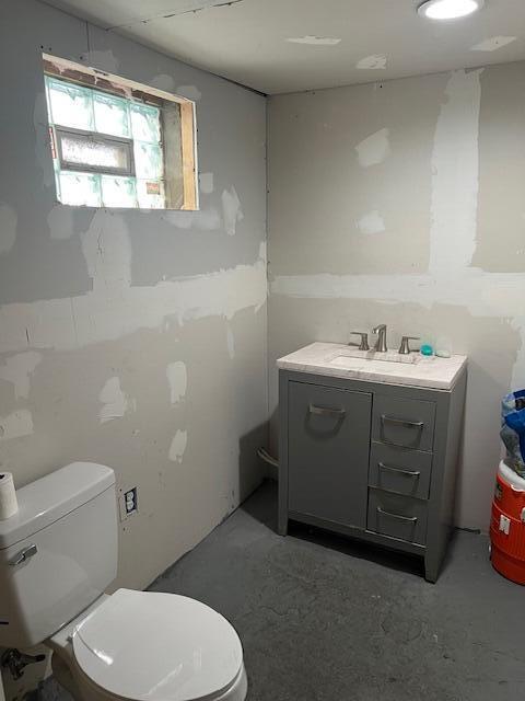 bathroom with toilet, concrete floors, and vanity