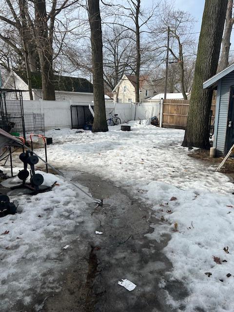 snowy yard featuring a fenced backyard