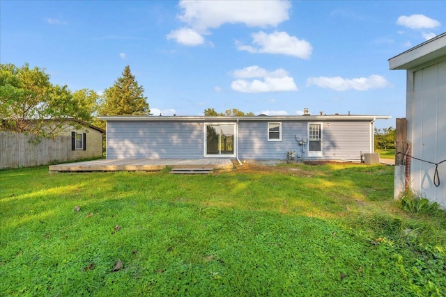 rear view of house featuring a deck, central AC unit, a lawn, and fence