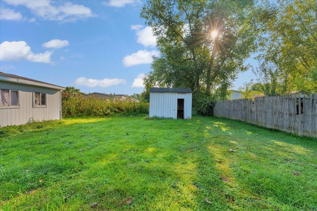 view of yard featuring an outdoor structure, fence, and a storage shed