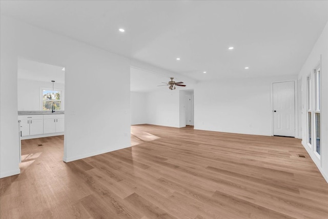 unfurnished living room with ceiling fan, a sink, light wood-style flooring, and recessed lighting