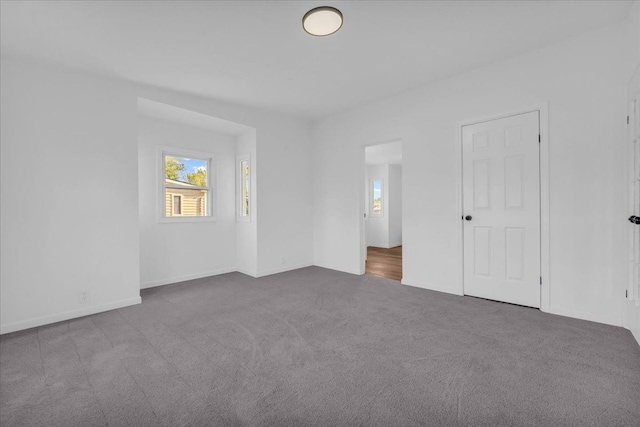 unfurnished bedroom featuring multiple windows, baseboards, and carpet flooring