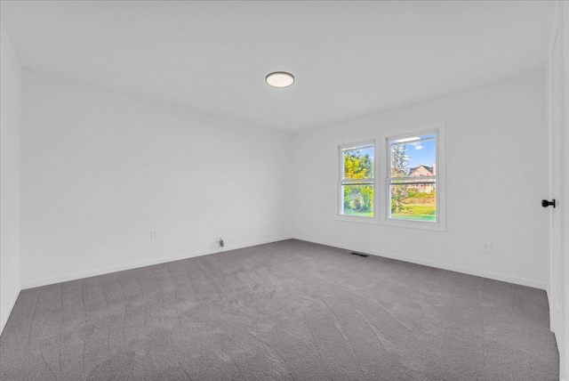 carpeted spare room featuring visible vents and baseboards