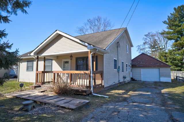 view of front of house with a porch, a shingled roof, an outdoor structure, a garage, and aphalt driveway