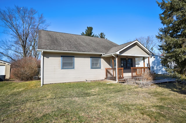 view of front of house with a deck, a front lawn, and a shingled roof