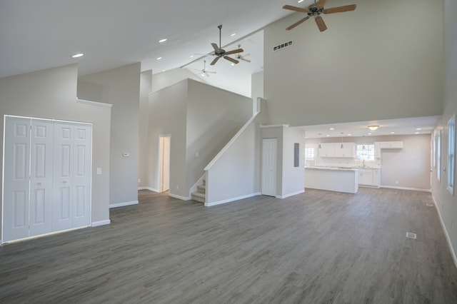 unfurnished living room featuring stairway, wood finished floors, visible vents, and baseboards