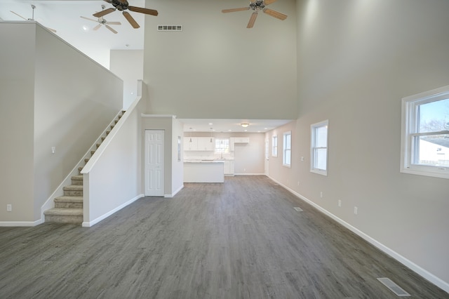 unfurnished living room featuring a wealth of natural light, visible vents, and stairs