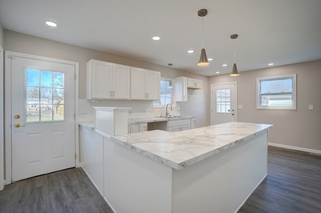 kitchen featuring light stone counters, dark wood finished floors, a sink, decorative backsplash, and white cabinets