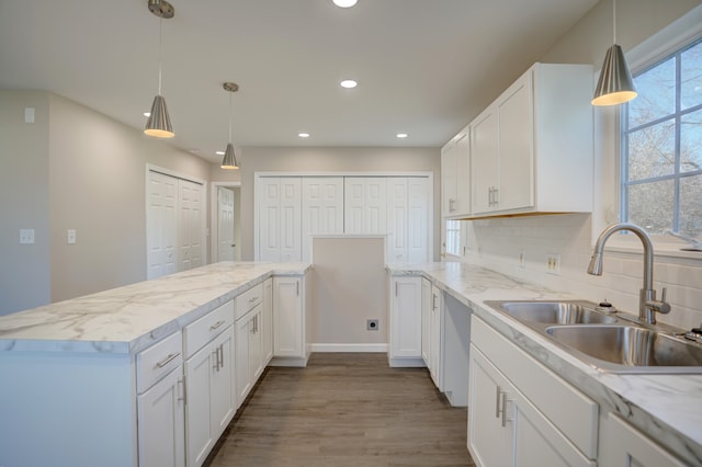 kitchen with decorative backsplash, a peninsula, white cabinets, and a sink