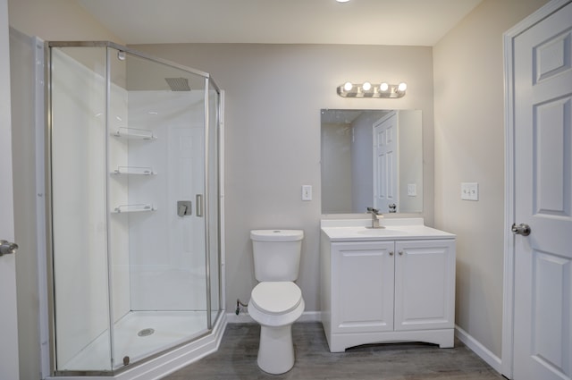 full bath with toilet, a stall shower, wood finished floors, baseboards, and vanity