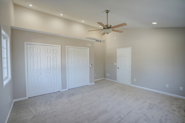 unfurnished bedroom featuring visible vents, two closets, high vaulted ceiling, carpet floors, and baseboards