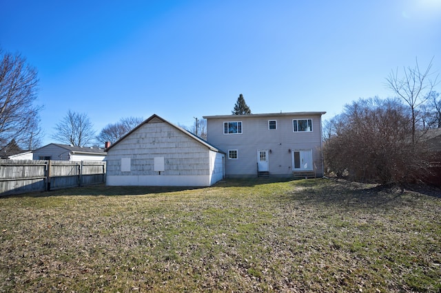 rear view of property featuring entry steps, fence, and a lawn