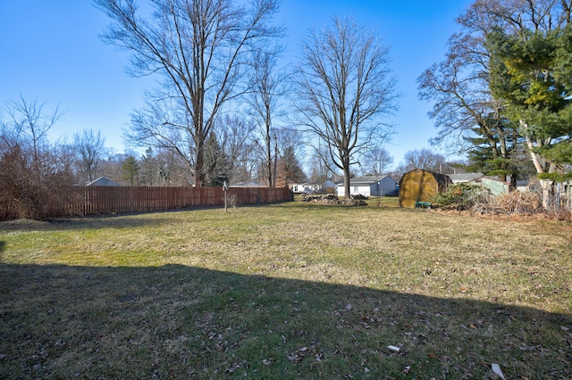 view of yard featuring an outbuilding, a storage unit, and fence