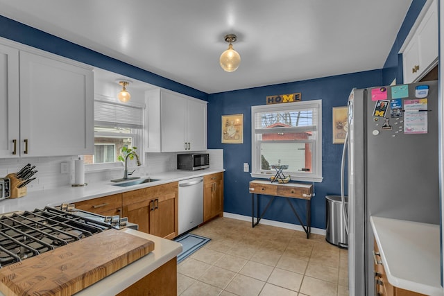 kitchen with light tile patterned floors, tasteful backsplash, light countertops, appliances with stainless steel finishes, and a sink