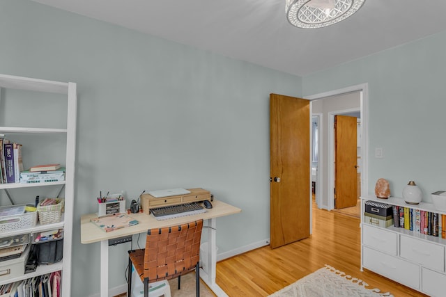 office space with light wood-type flooring and baseboards