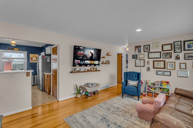 living room featuring light wood finished floors, recessed lighting, visible vents, and baseboards