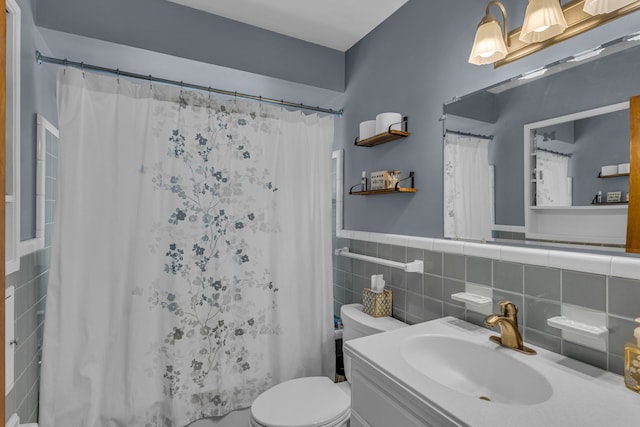 bathroom with tile walls, toilet, wainscoting, vanity, and a shower with curtain