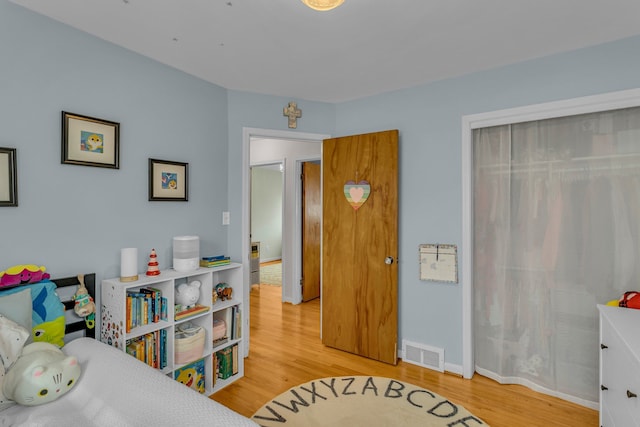 bedroom with light wood-style flooring, a closet, visible vents, and baseboards