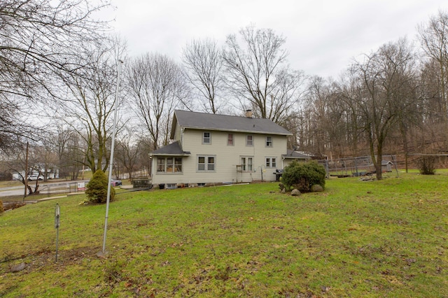 rear view of house featuring a chimney, fence, and a yard