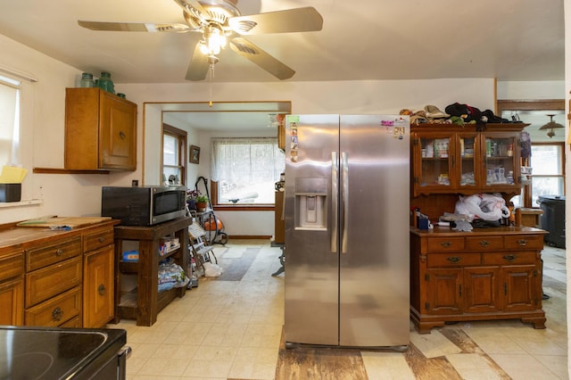 kitchen with stainless steel appliances, brown cabinetry, ceiling fan, and glass insert cabinets