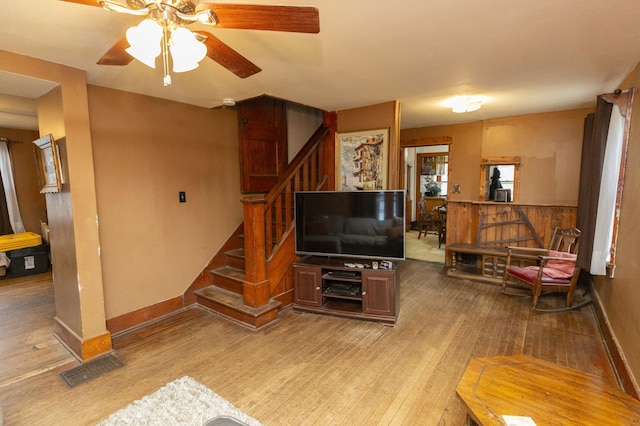 living room featuring baseboards, visible vents, stairway, and hardwood / wood-style floors