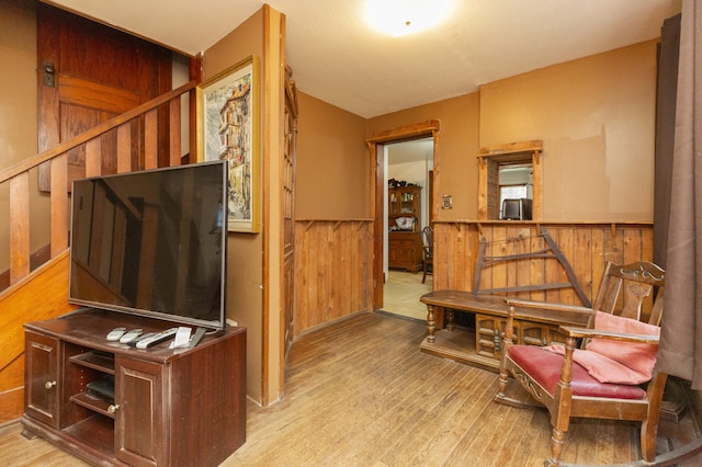 sitting room featuring wood walls, wood finished floors, and wainscoting