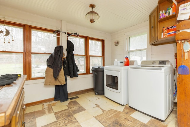 clothes washing area with baseboards, cabinet space, light floors, and separate washer and dryer