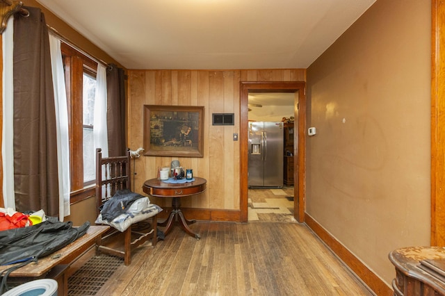 corridor featuring baseboards, wood finished floors, and wooden walls