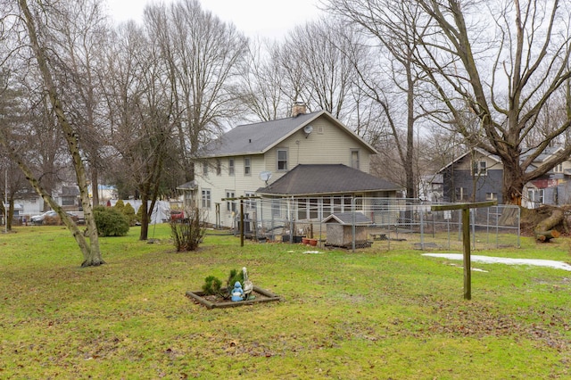 back of house featuring a lawn, a chimney, an outdoor structure, and fence