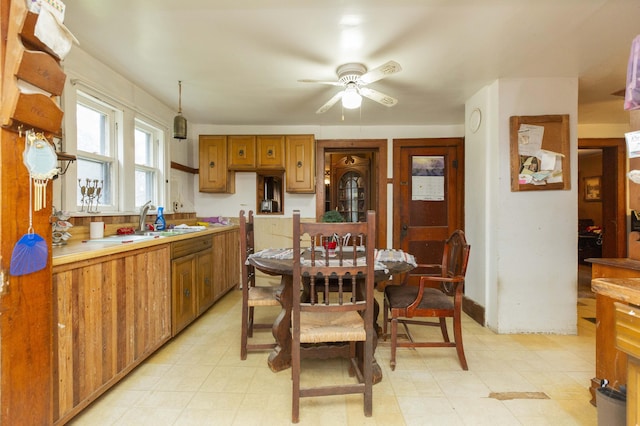 kitchen with brown cabinets, light floors, light countertops, a ceiling fan, and a sink