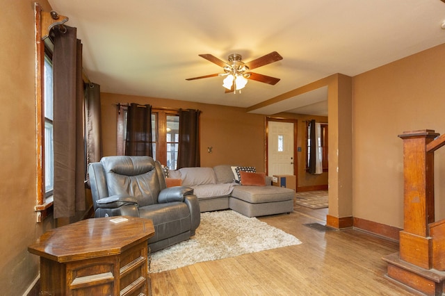 living room featuring baseboards, a ceiling fan, and wood finished floors