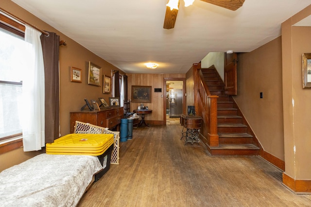 interior space featuring stairs, a ceiling fan, baseboards, and wood finished floors