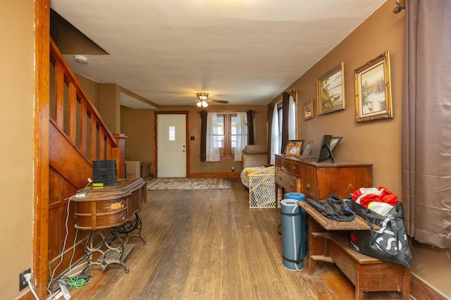 foyer entrance with stairs, ceiling fan, and wood finished floors