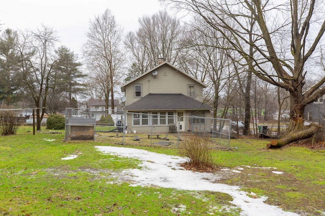 back of property with dirt driveway, fence, and a yard