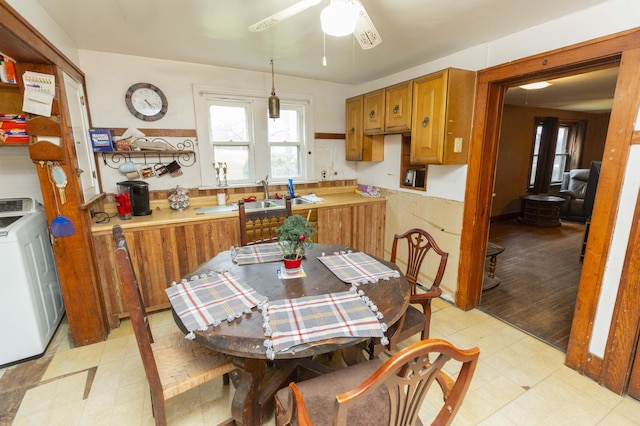 kitchen with light floors, washer / clothes dryer, brown cabinetry, and a sink