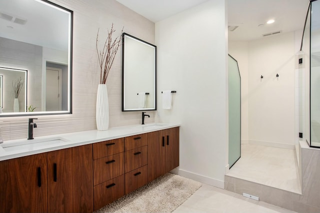 bathroom featuring double vanity, a stall shower, a sink, and visible vents