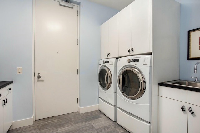 laundry area with washing machine and dryer, a sink, baseboards, light wood-type flooring, and cabinet space