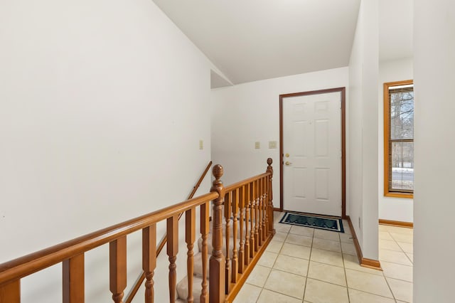 entryway with light tile patterned floors, baseboards, and vaulted ceiling