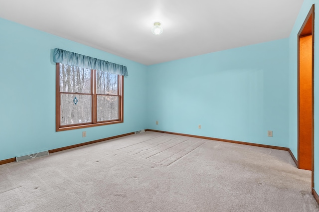 carpeted spare room featuring baseboards and visible vents