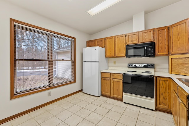 kitchen featuring black microwave, light countertops, electric range oven, and freestanding refrigerator