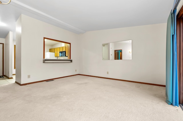 spare room with light colored carpet, visible vents, and baseboards