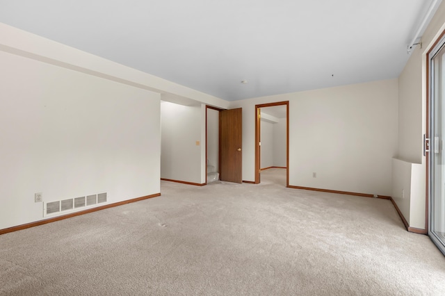 empty room featuring light colored carpet, visible vents, and baseboards