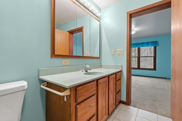 half bath with tile patterned flooring, baseboards, vanity, and toilet