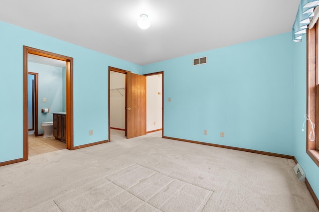 unfurnished bedroom featuring carpet, visible vents, a walk in closet, and baseboards