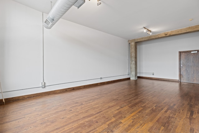 empty room with rail lighting, baseboards, and hardwood / wood-style flooring