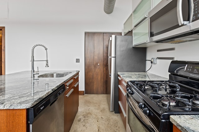 kitchen featuring stainless steel appliances, glass insert cabinets, a sink, and light stone countertops