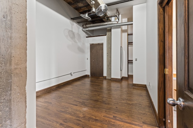 empty room featuring wood finished floors, a towering ceiling, and baseboards