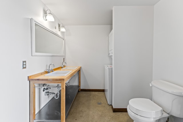 bathroom with washer / dryer, baseboards, toilet, vanity, and concrete floors