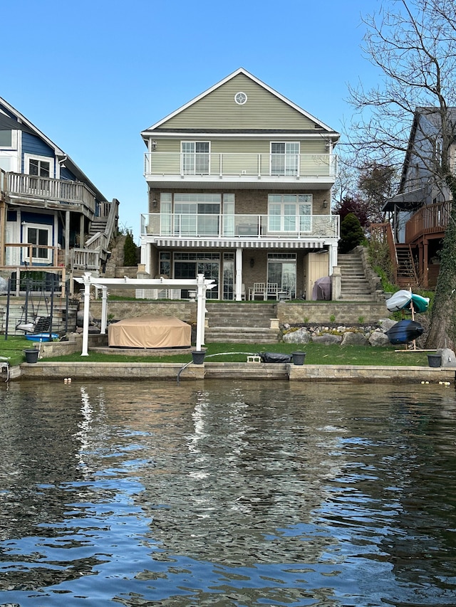 rear view of property featuring a water view, stairway, and a balcony